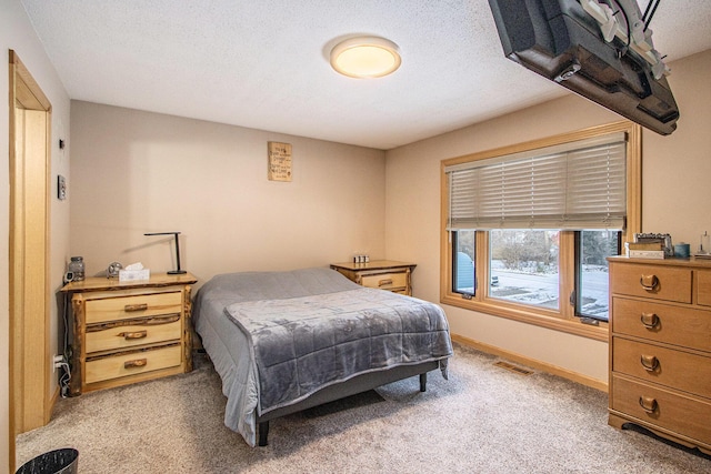 bedroom with a textured ceiling and light colored carpet