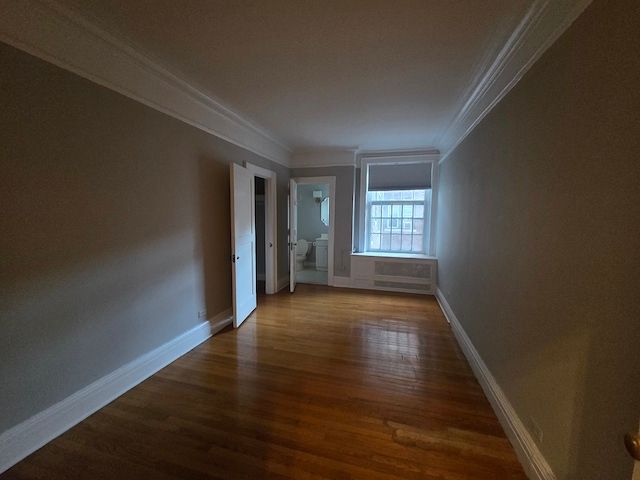 unfurnished room featuring ornamental molding and dark wood-type flooring