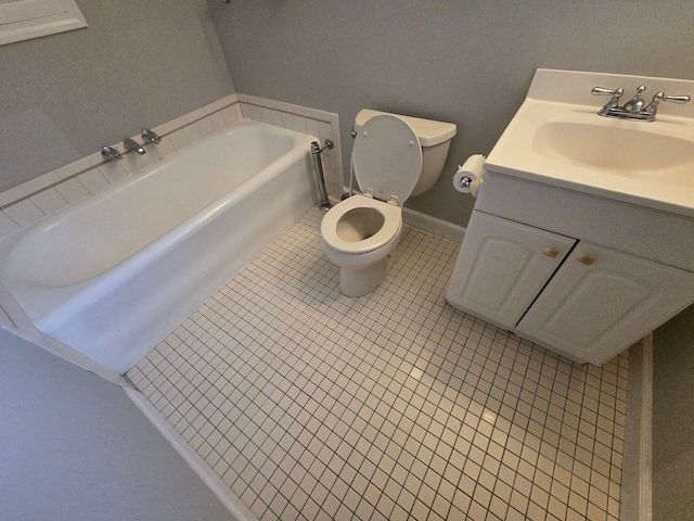 bathroom with toilet, a washtub, vanity, and tile patterned flooring