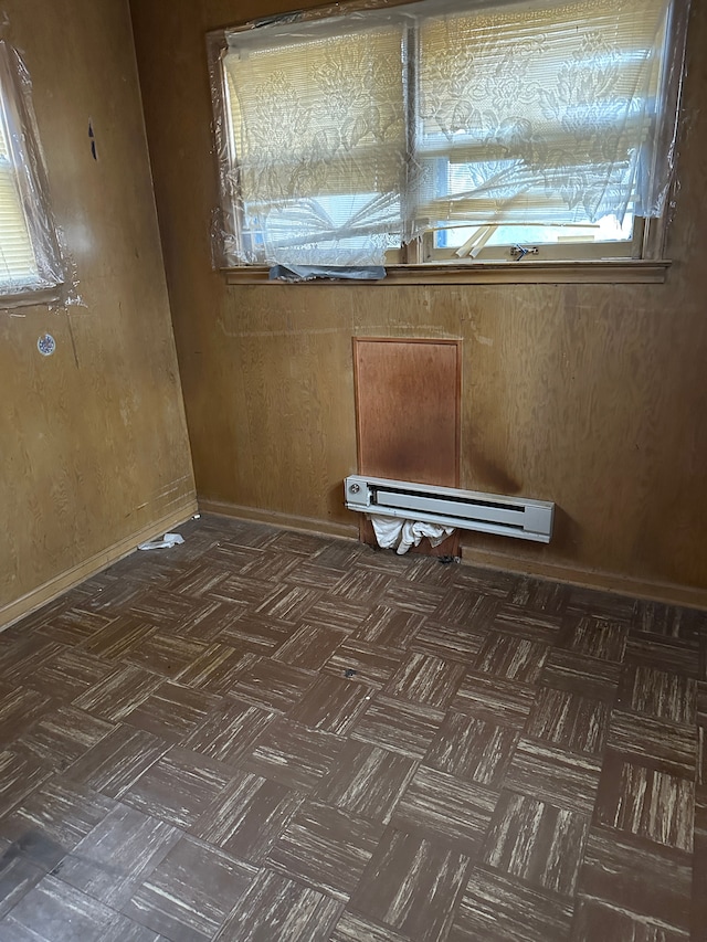 spare room featuring baseboard heating and wooden walls