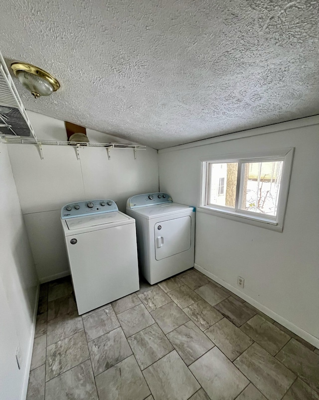 laundry room with a textured ceiling and washing machine and clothes dryer