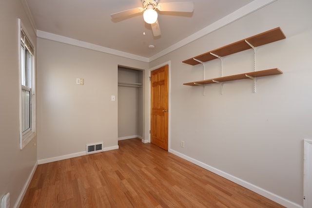 unfurnished bedroom with light wood-type flooring, ceiling fan, a closet, and crown molding