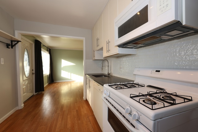 kitchen with tasteful backsplash, white appliances, wood-type flooring, white cabinets, and sink