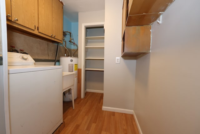 washroom featuring cabinets, light wood-type flooring, water heater, and washer / clothes dryer