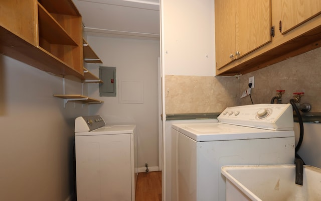 clothes washing area with cabinets, sink, electric panel, and independent washer and dryer