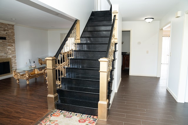 stairway featuring a fireplace, hardwood / wood-style flooring, and ornamental molding