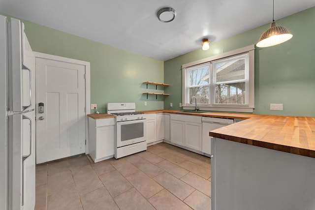 kitchen featuring white appliances, sink, butcher block countertops, decorative light fixtures, and white cabinetry