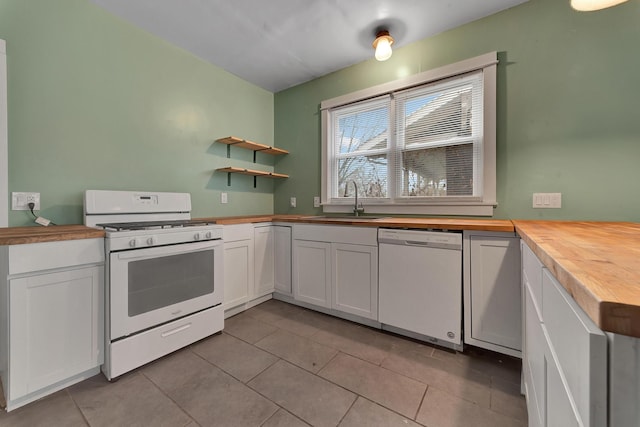 kitchen featuring white appliances, wooden counters, sink, light tile patterned flooring, and white cabinetry