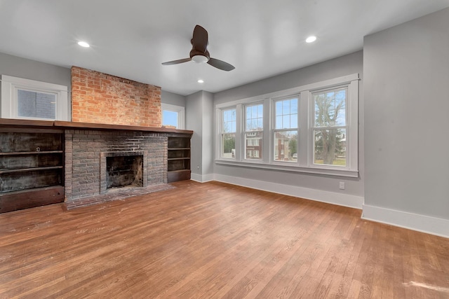 unfurnished living room with a brick fireplace, light hardwood / wood-style flooring, and ceiling fan