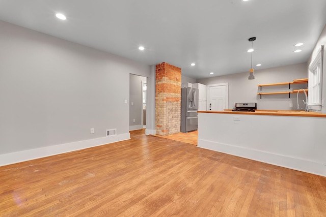 kitchen with stainless steel appliances, hanging light fixtures, and light hardwood / wood-style floors