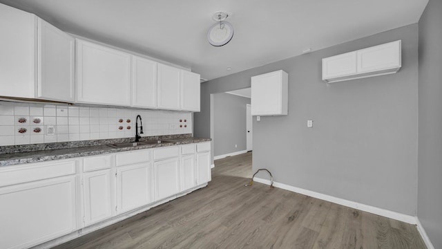 kitchen with white cabinets, light wood-type flooring, and tasteful backsplash