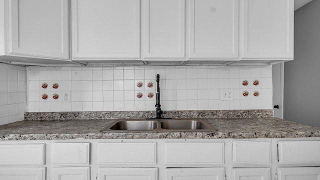 kitchen with white cabinets, decorative backsplash, and sink