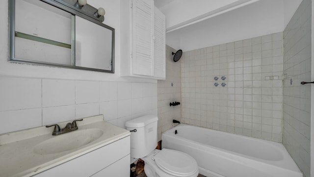 full bathroom featuring vanity, tiled shower / bath combo, tile walls, and toilet