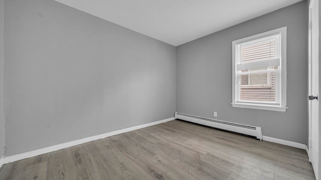 unfurnished room with a healthy amount of sunlight, light wood-type flooring, and a baseboard heating unit