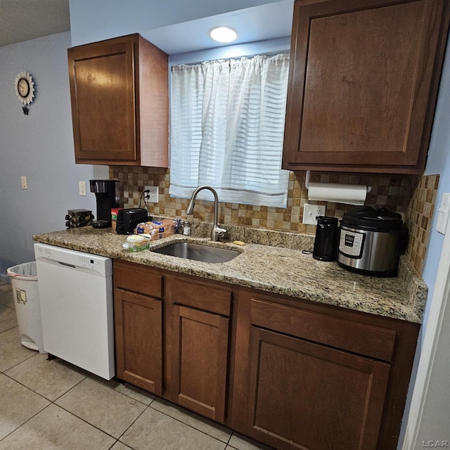 kitchen featuring light stone countertops, tasteful backsplash, white dishwasher, sink, and light tile patterned flooring