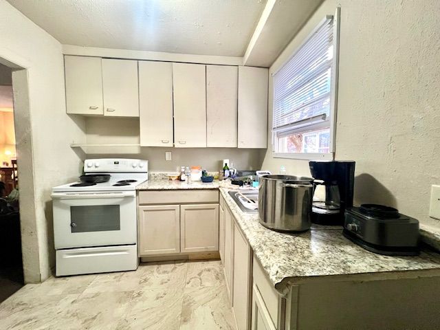 kitchen featuring white range with electric cooktop and light stone counters