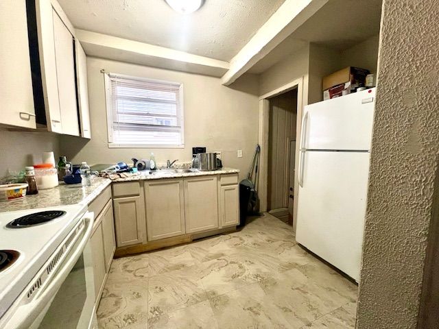 kitchen featuring a textured ceiling, white appliances, and sink