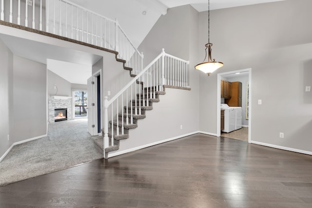 interior space featuring washing machine and dryer, a stone fireplace, high vaulted ceiling, and hardwood / wood-style flooring