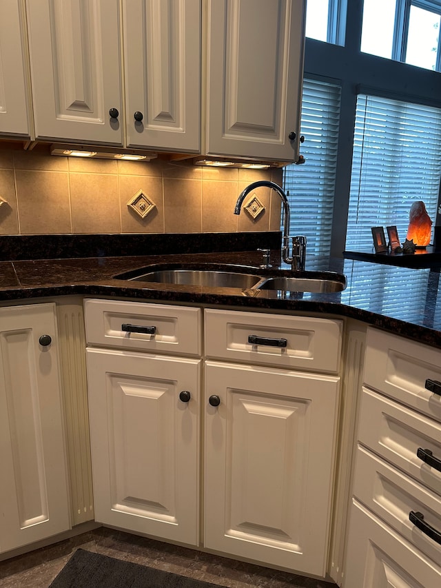 kitchen featuring white cabinets, tasteful backsplash, dark stone countertops, and sink