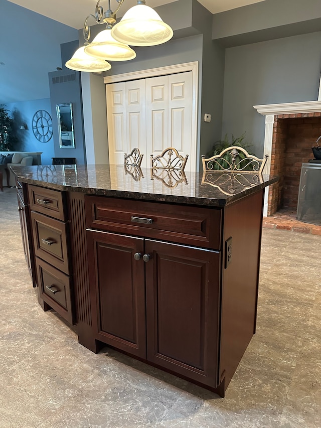 kitchen featuring dark brown cabinetry, pendant lighting, and dark stone counters