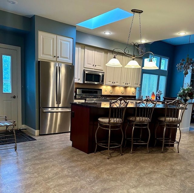 kitchen featuring a skylight, a center island, hanging light fixtures, a kitchen breakfast bar, and appliances with stainless steel finishes