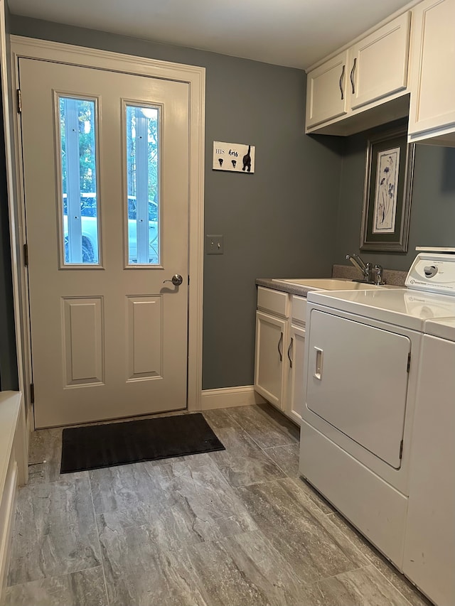 laundry area with cabinets, independent washer and dryer, sink, and light hardwood / wood-style flooring