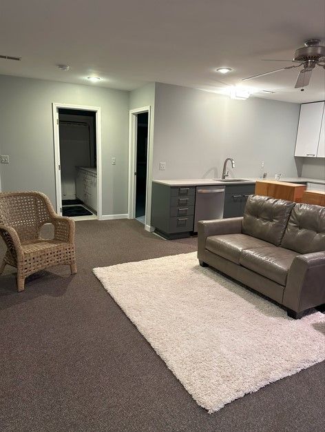 living room featuring carpet, ceiling fan, and sink