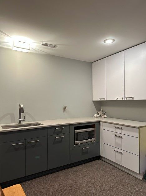 kitchen with white cabinetry, sink, and dark carpet