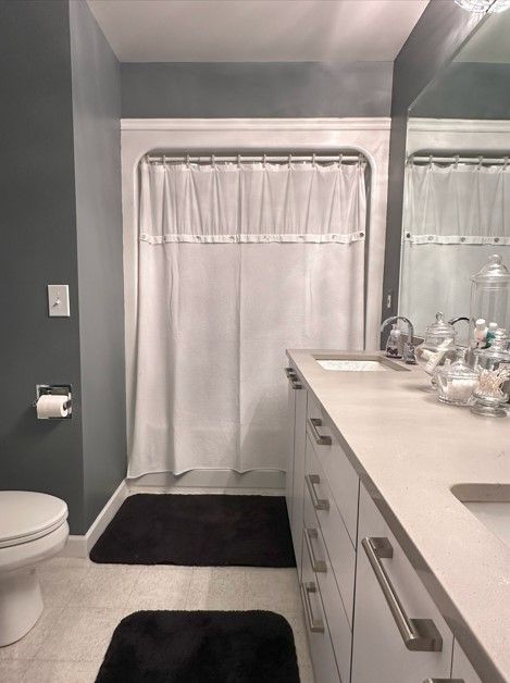 bathroom featuring curtained shower, tile patterned flooring, vanity, and toilet