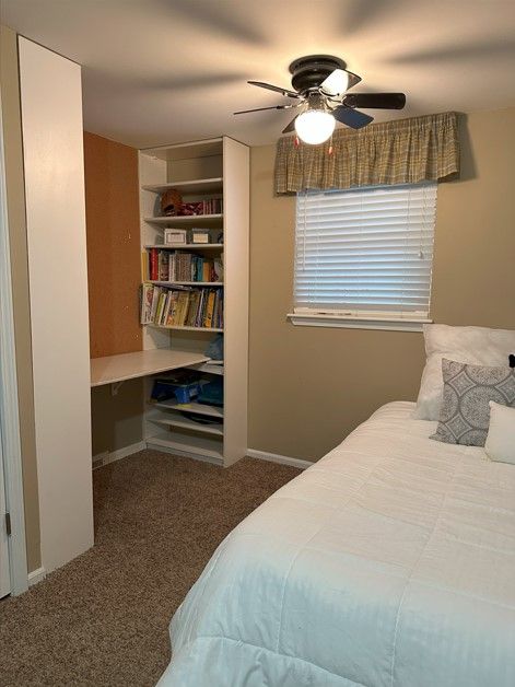 carpeted bedroom featuring ceiling fan and built in desk