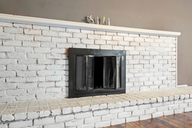 interior details with wood-type flooring and a brick fireplace