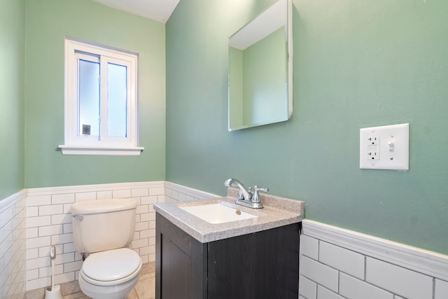 bathroom featuring tile patterned floors, vanity, tile walls, and toilet