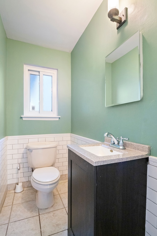 bathroom featuring toilet, vanity, tile patterned floors, and tile walls