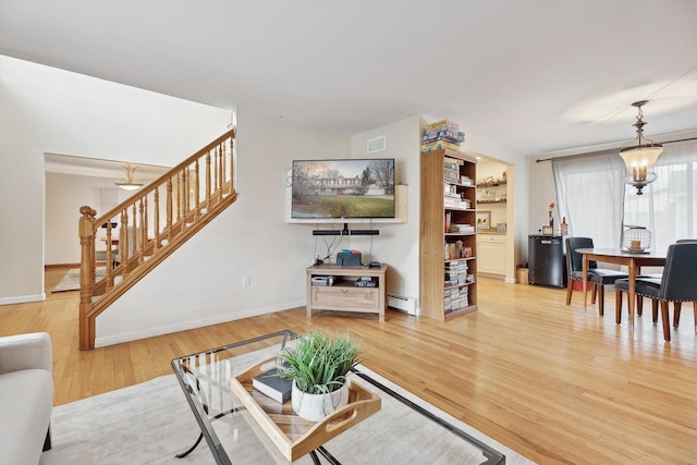 living room featuring an inviting chandelier, hardwood / wood-style flooring, and a baseboard radiator