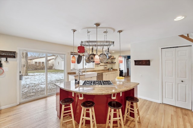 kitchen featuring a center island, light hardwood / wood-style flooring, decorative light fixtures, a breakfast bar area, and appliances with stainless steel finishes