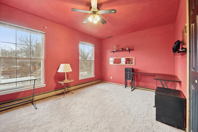 living area with baseboard heating, ceiling fan, carpet flooring, and a healthy amount of sunlight