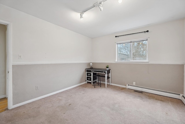 unfurnished room with carpet, track lighting, and a baseboard heating unit