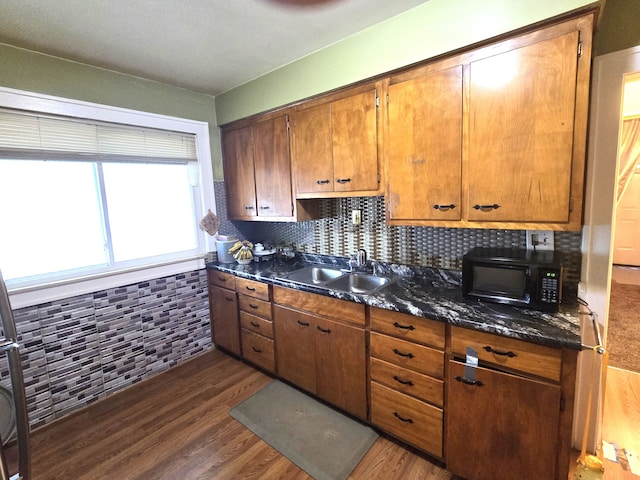 kitchen featuring dark stone countertops, decorative backsplash, sink, and dark hardwood / wood-style floors