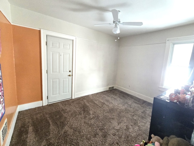 unfurnished room featuring dark carpet and ceiling fan