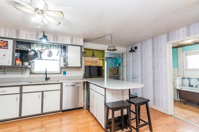 kitchen featuring dishwasher, white cabinets, hanging light fixtures, and sink