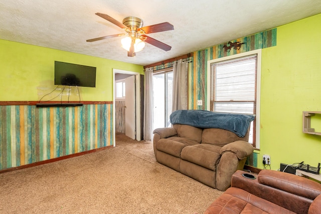 carpeted living room featuring ceiling fan and a textured ceiling