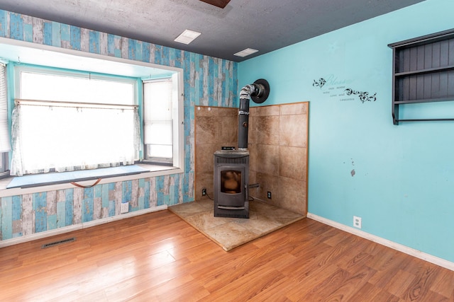 misc room with wood-type flooring, a wood stove, and a wealth of natural light