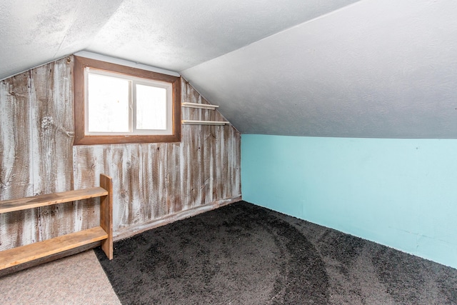 bonus room with vaulted ceiling, carpet, and a textured ceiling