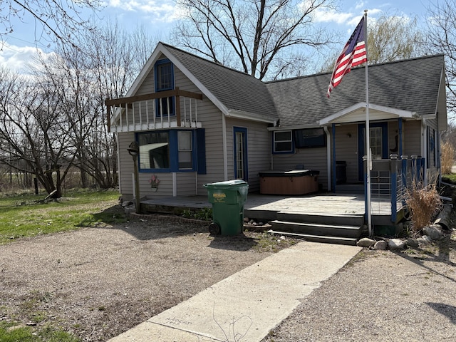 bungalow with roof with shingles and a hot tub
