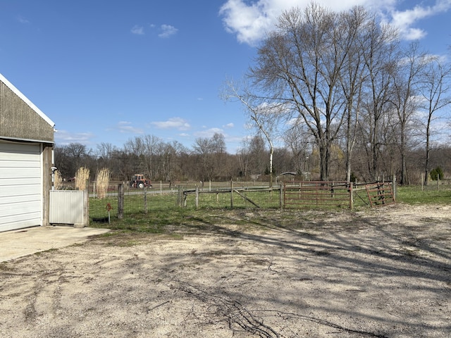 view of yard with fence, a gate, and a rural view
