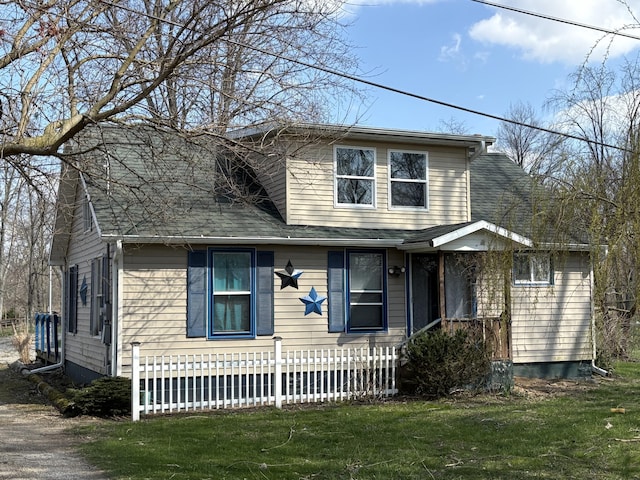 view of front of home with roof with shingles, fence, and a front lawn