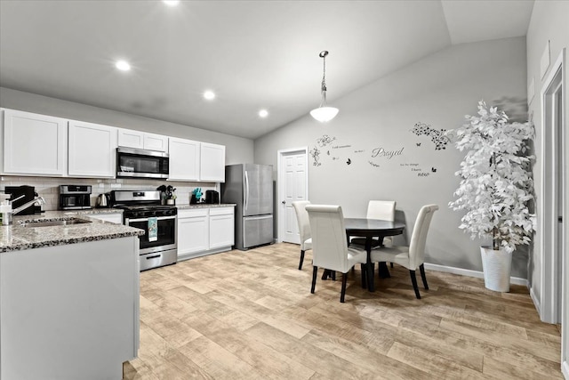 kitchen with appliances with stainless steel finishes, vaulted ceiling, pendant lighting, and sink