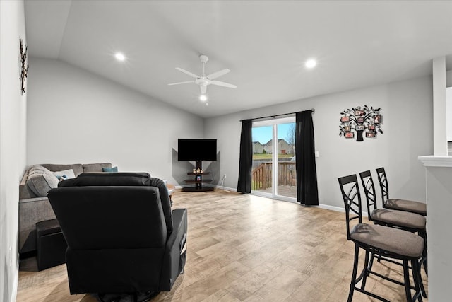 living room with ceiling fan, light hardwood / wood-style floors, and vaulted ceiling