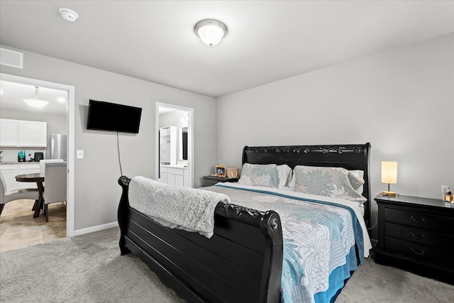 bedroom featuring stainless steel refrigerator, ensuite bath, and light colored carpet