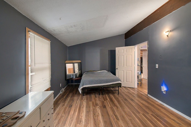 bedroom featuring a textured ceiling, dark hardwood / wood-style floors, and lofted ceiling